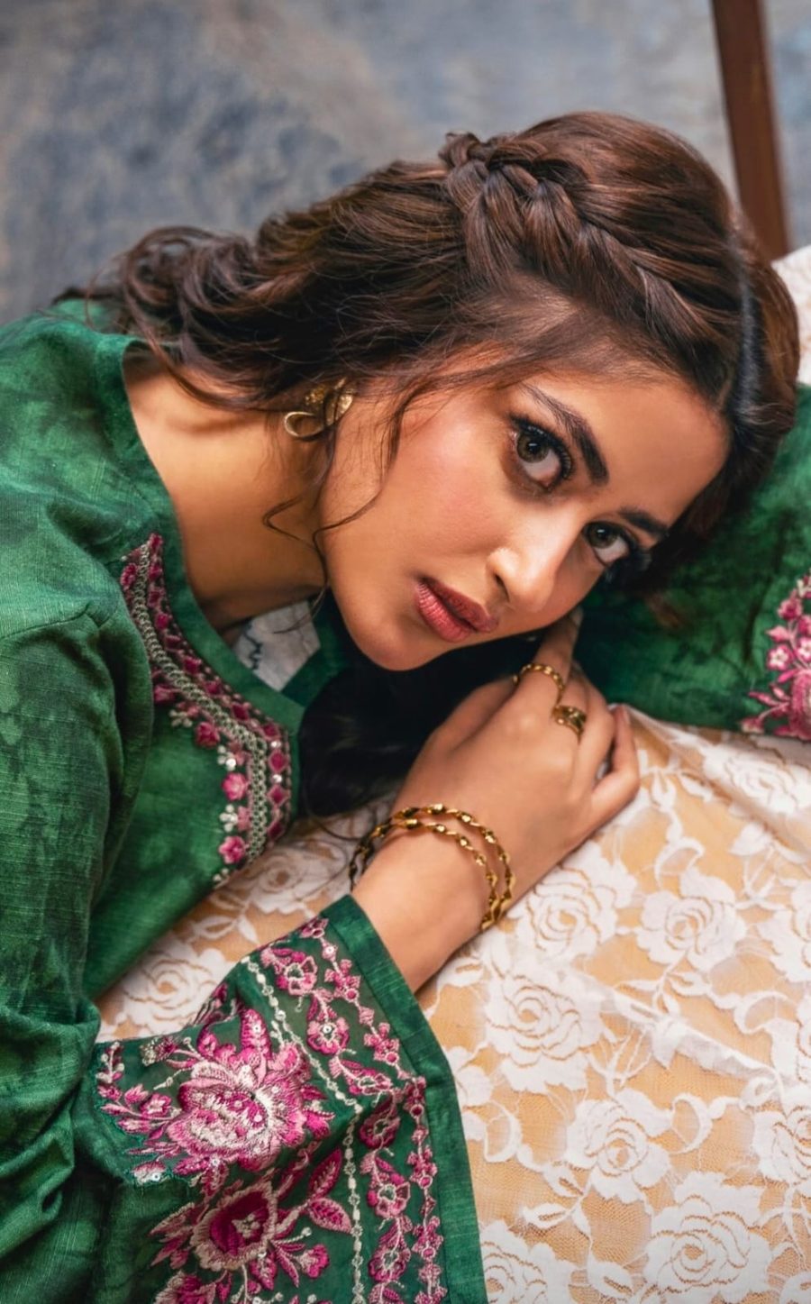 Model in emerald green resting on a gold ring and paired bangles