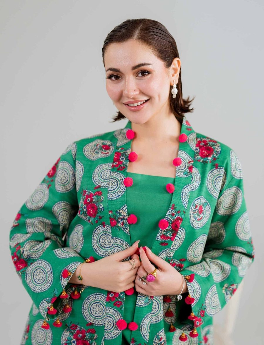 Model in a printed green jacket wearing pearl drops and ring stacks