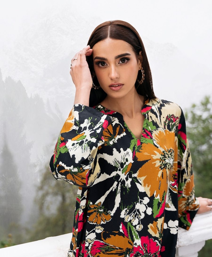 Model in a bold floral print wearing textured gold hoop earrings